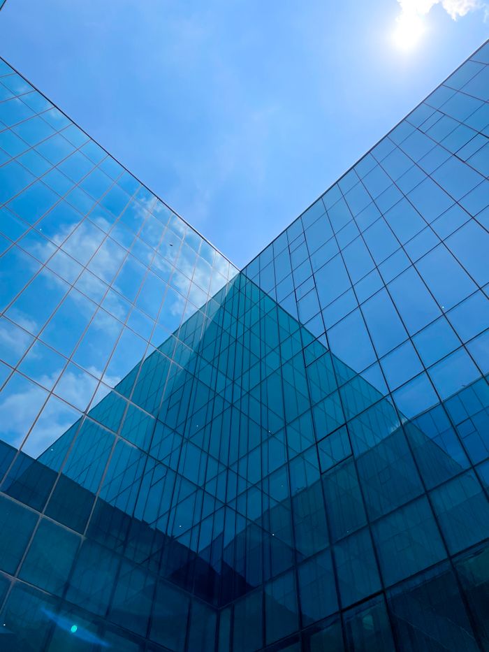 Film miroir sans tain : la solution idéale pour se protéger des regards indiscrets à la maison Low angle view of a modern glass skyscraper against a clear blue sky, showcasing urban architecture.