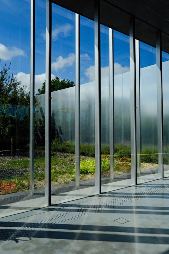 Futuristic glass building with natural reflections and sunlight shadows.