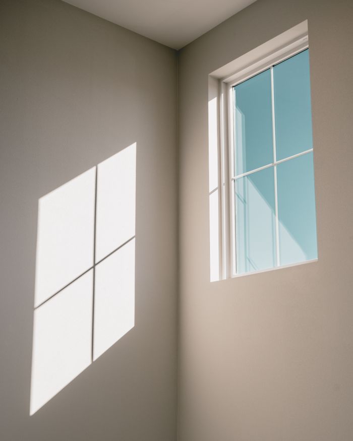 Low angle of window with glazing bars in light simple room with shadow on white wall